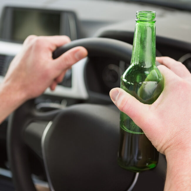osoba trzymająca butelkę w samochodzie
